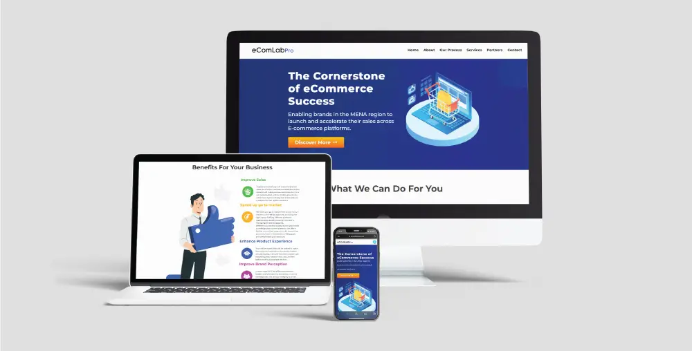 E-commerce website displayed on three devices: a desktop, laptop, and smartphone. The desktop and smartphone screens show a page titled 'The Cornerstone of e-Commerce Success' with an illustration of a digital storefront and a 'Learn More' button. The laptop screen highlights 'Benefits For Your Business' with numbered points and an illustration of a person holding a large blue shopping bag. All devices showcase the eComLabs branding.