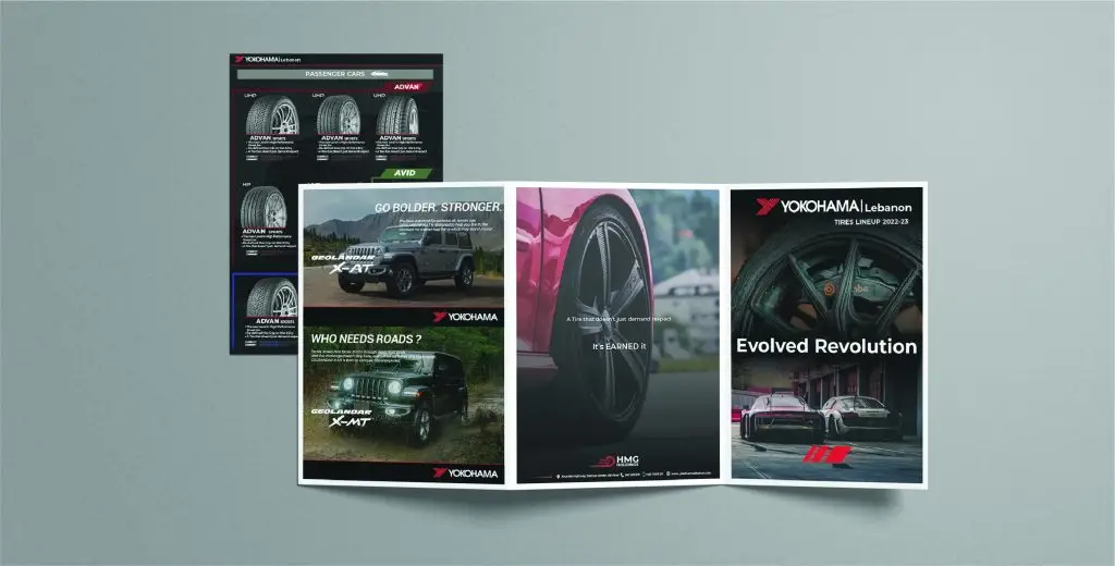 Promotional materials for Yokohama tires, including an open brochure with four pages showcasing various tire models and features, and a flyer positioned behind the brochure highlighting specifications and benefits. The materials feature high-quality images of vehicles and tires, emphasizing the performance and reliability of Yokohama tires.